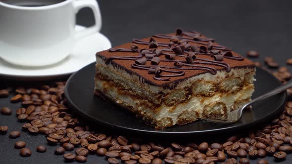 Portion of Traditional Italian Tiramisu dessert, cup of espresso coffee and coffee beans