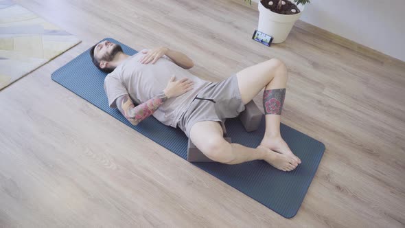 Young Man Doing Breath Awareness Exercise Lying on Yoga Mat