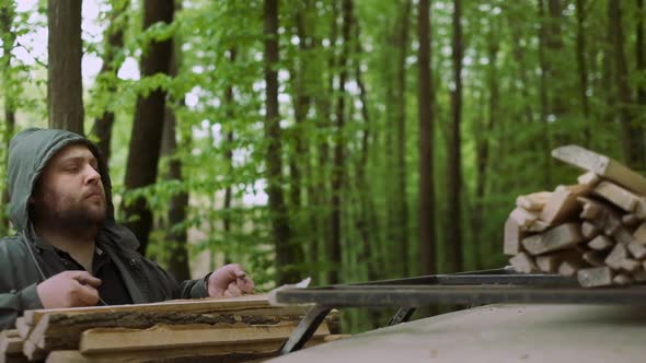 Slow Motion Of Casual Strong Man Works with Firewood Near Car in Wild Deciduous Forest.