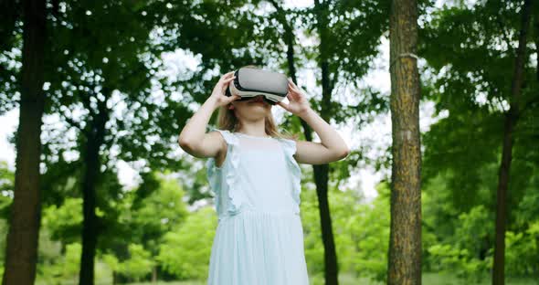 A Teenage Girl Wears VR Glasses and Play Simulation 3D Video Game in Nature