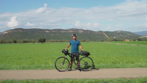 Traveler Cyclist Man Looking at Camera with a Bicycle in Nature