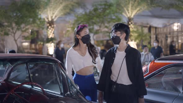 A Couple Wearing Black Mask Was Standing in Front of a Beautiful Car in a Corner Looking at the Car