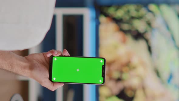 Closeup of Man Holding Vertical Smartphone with Green Screen in Online Conference or Group Video
