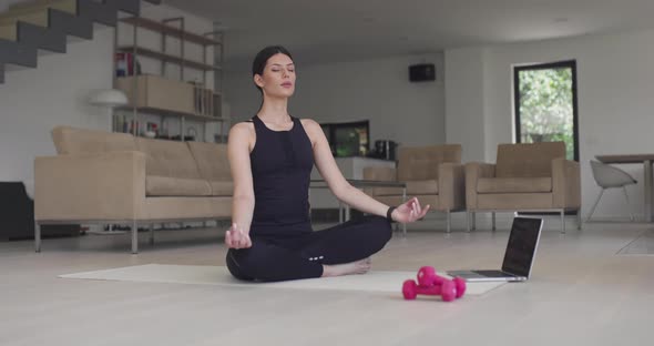 Woman in Sportswear Doing Stretching Exercises While Watching Yoga Training Class on Computer Laptop