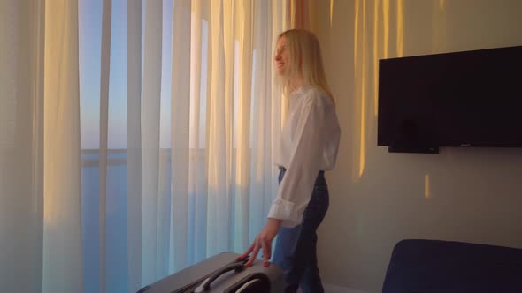 Portrait of tourist visiting hotel, standing at window and admiring beautiful