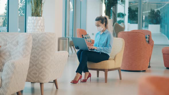 A Woman in a Face Mask is Working Remotely From the Cafe