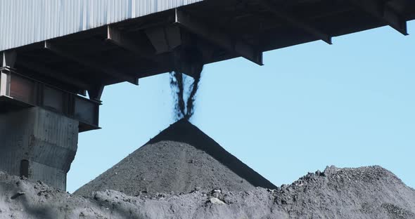 Black Coal Poured Into Huge Mineral Pile From Conveyor Against Blue Sky