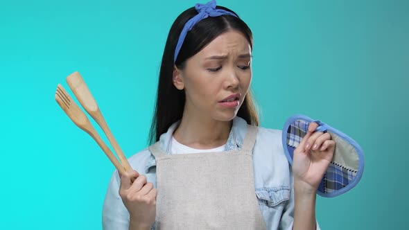 Confused Housewife Holding Kitchenware Shrugging Shoulders, Lack of Experience