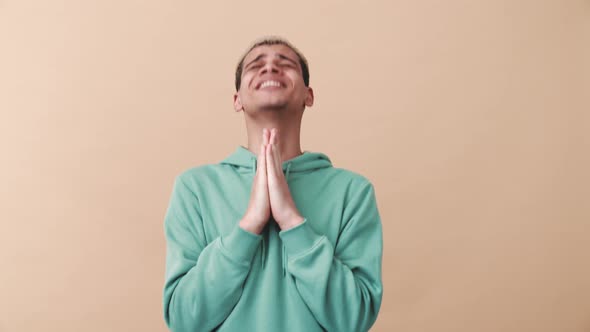 Smiling curly-haired man wearing blue hoodie hoping for something