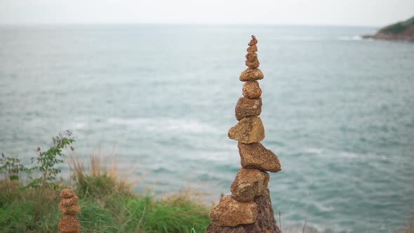 A Cairn Is Stands on Top of A Cliff Against the Blue Sea. Heap of Stones Close-Up