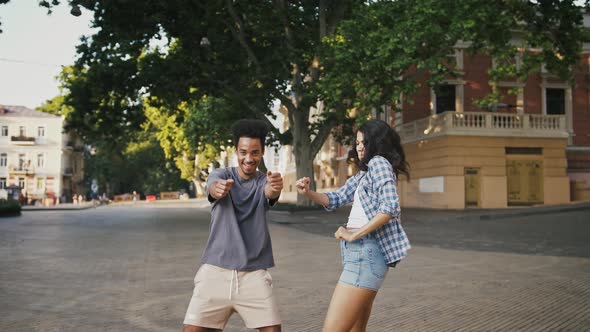 Afroamerican Male and Female are Smiling and Dancing at City Square