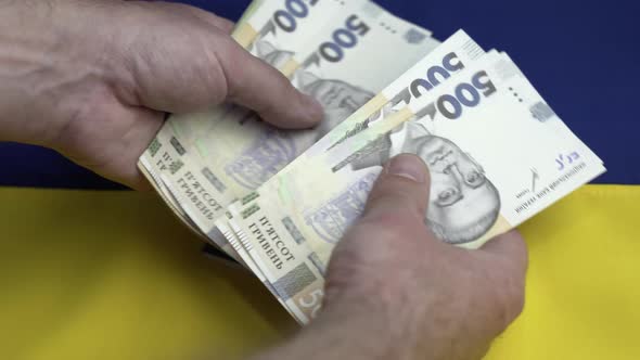 Recount Money Ukrainian Hryvnia Bills in Mans Hands Closeup on Ukrainian Flag Background