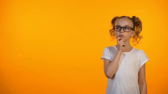 Pensive Preteen Girl Thinking Isolated on Orange Background, Planning Education