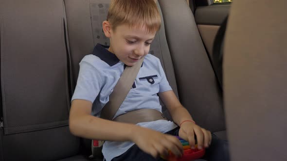 A Boy Holds an Antistress Toy Pop It in His Hands While Sitting in the Car