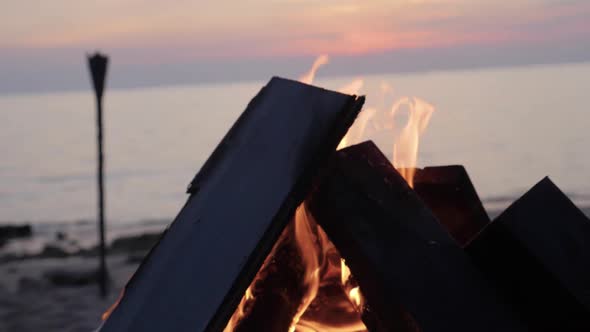 Bonfire by the beach at sunset in Asia - ultra slow motion panning right