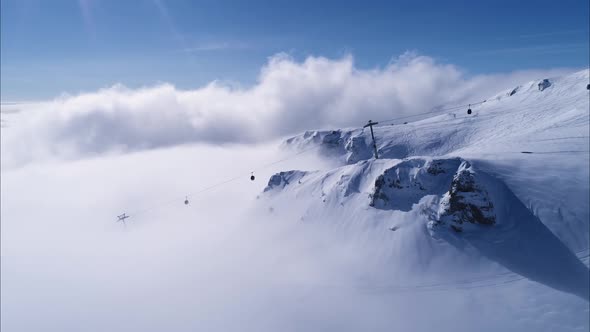 Aerial view over gondola on the cliff with snowy mountain ridge valley with in winter