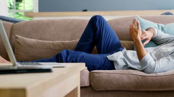 Happy man using mobile phone in living room