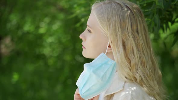 A Woman Rejoices at the Smell of Flowers Without a Medical Mask in the Park