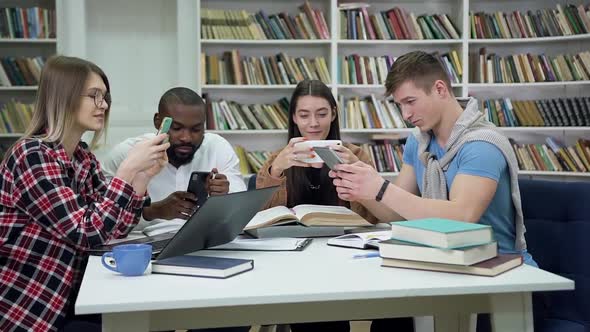 Friends Playing on their Phones During Break Between Preparation for Exams in the Library