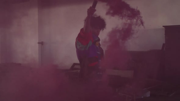 Mixed race man holding purple flare walking through an empty building