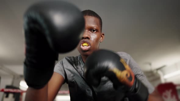 Motivational Sport Portrait of African Man Boxer Throwing Punches During Training in Boxing Club