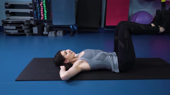 Fit Women Doing Abdominal Exercises in Gym Using TRX Straps