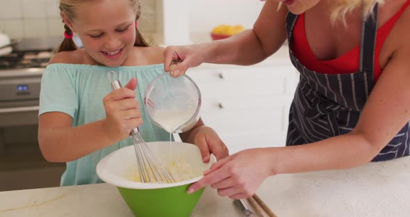 Caucasian mother and daughter baking together in the kitchen at home