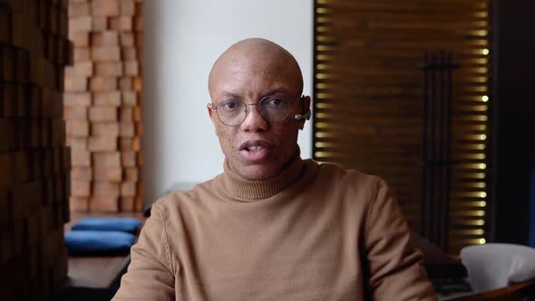 An African American Man is Negotiating Remotely Through a Video Chat Looking at the Camera