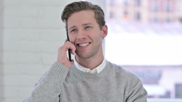 Portrait of Cheerful Creative Young Man Talking on Smartphone 