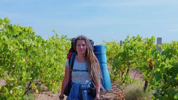 Girl with Dreadlocks Goes Past Vineyards