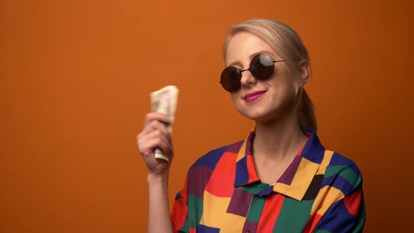 Style blonde in 90s shirt with money on orange background