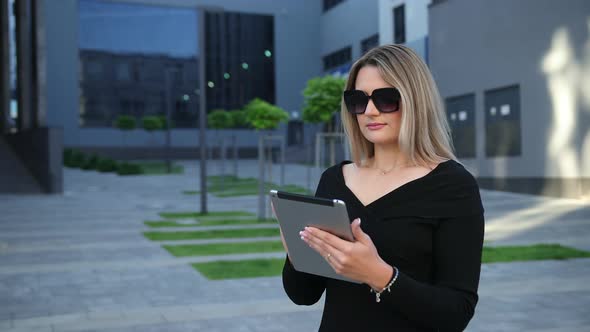 Beautiful Young Woman Wearing Sunglasses Using Tablet Pc in the City