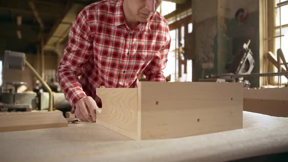 Bolding Caucasian Middleaged Male in Red Plaid Shirt Assembling Wooden Box in Joinery in Slowmotion