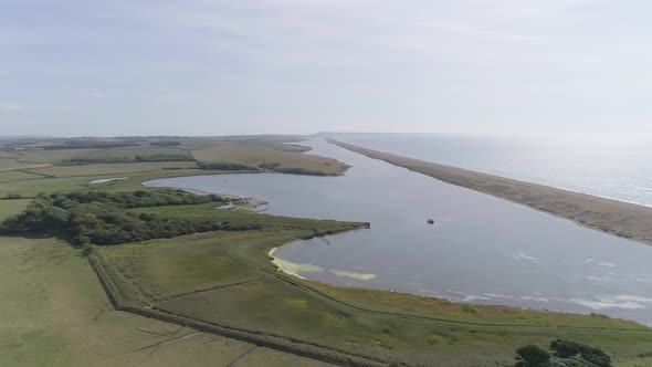 Aerial tracking from right to left along Chesil Beach and the fleet lagoon rotating the shot out to