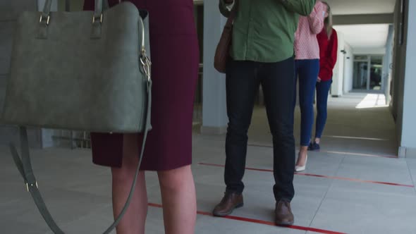 People wearing face masks using smartphones while standing in queue