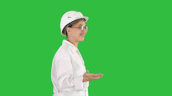 Young scientist in lab coat and hardhat walking and saying