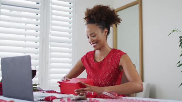 Happy mixed race woman on a valentines date video call, opening gift