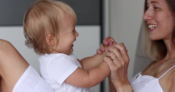 Adorable Infant Baby Girl Daughter Playing Patty Cake with Young Caucasian Mother at Home