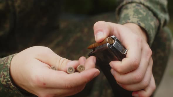 A Russian Military Man Loads Cartridges Into the Magazine of a Kalashnikov Assault Rifle  Closeup