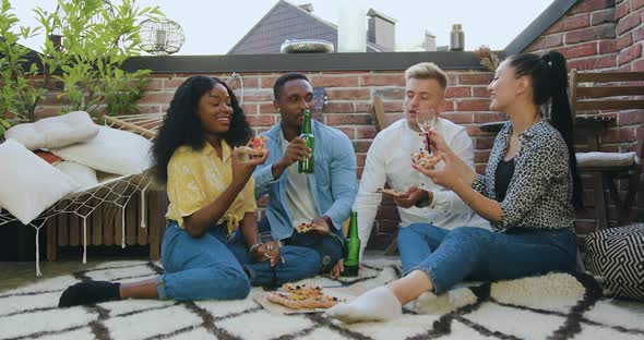 Multiracial Friends which Resting on the Balcony and Drinking Wine, Beer and Eating Pizza