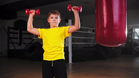 A Little Boy Lifting Up Small Dumbbells in Both Hands