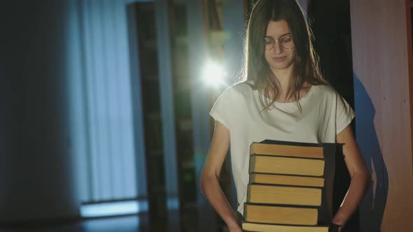 Female Student in Glasses Holds Stack of Books in Her Hands and Looks at Camera