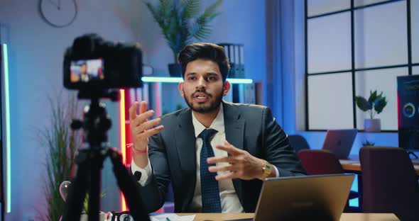 Businessman Recording Video for Internet Audience while Explaining Chart in Modern Evening Workroom