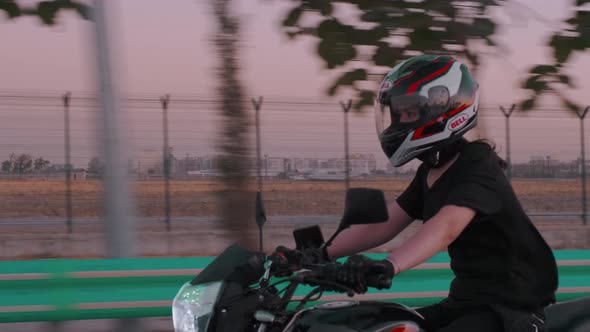 Woman Riding Motorcycle Down The Road In The Twilight