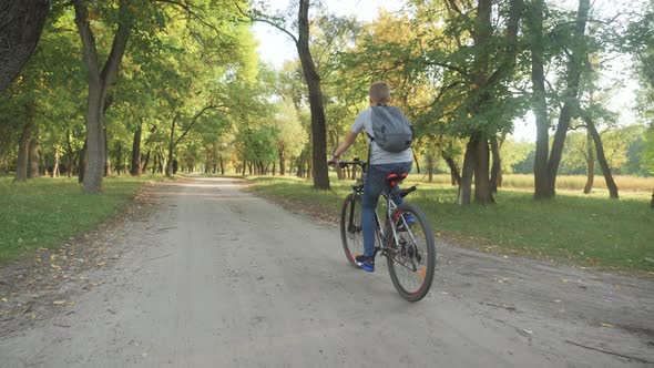 Teenage Boy Rides Bike in City Park at Sunny Day. Healthy Lifestyle Concept.