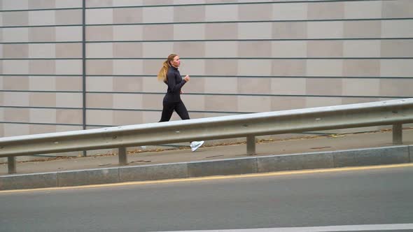 Fit woman jogging on sidewalk in city