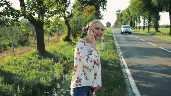 Girl Speaking on Phone While Hitchhiking.