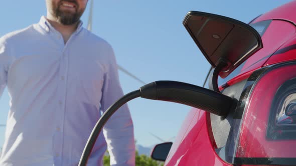 Handsome Stylish Mature Man Unplugging Charging Cord From Electric Vehicle 6K