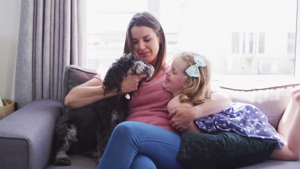 Caucasian mother and daughter having fun playing with a dog