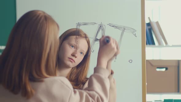 Reflection of a Red Haired Teenage Girl Writing an Inscription on a Mirror